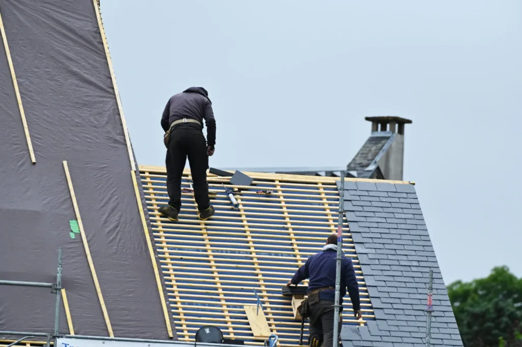 ouvrier couvreur sur un toit d'habiation en cours de rénovation